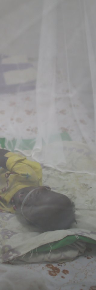 Ett barn ligger under ett myggnät på en säng i Sydsudan.