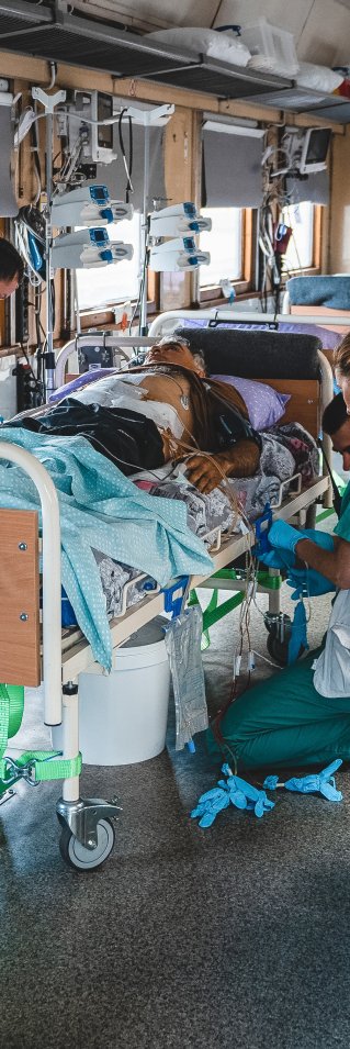 Personal på intensivvårdsavdelningen på Läkare Utan Gränsers tåg övervakar och stabiliserar en svårt krigsskadad patient under en resa från Pokvrosk i östra Ukraina till Lviv i västra Ukraina.