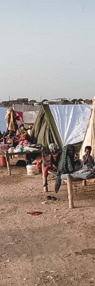 Människor sitter i tillfälliga skydd byggda på en väg i översvämningsdrabbade Pakistan.