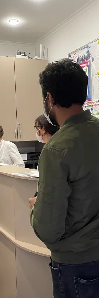 Personer står i kö vid receptionen på en vårdcentral