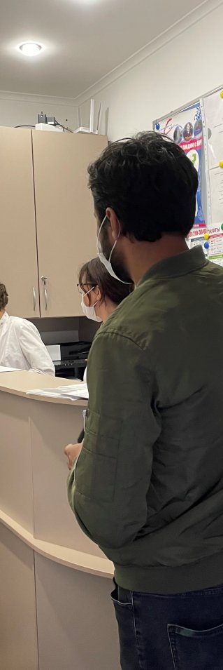 Personer står i kö vid receptionen på en vårdcentral