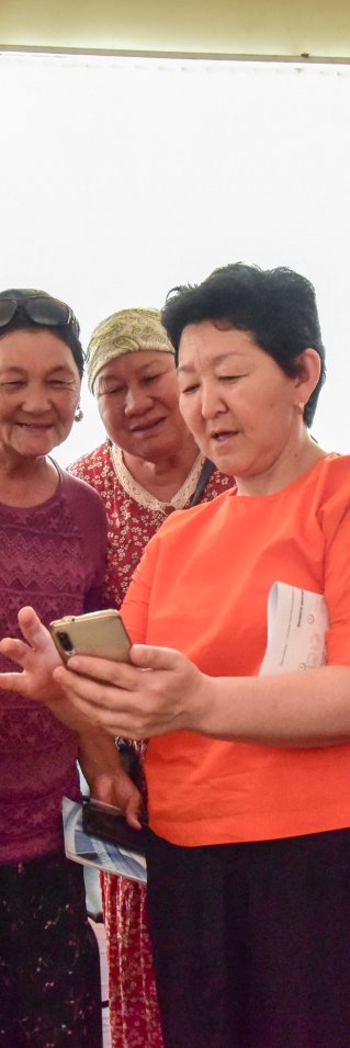 Fem kvinnor står bredvid varandra och kollar på en mobil