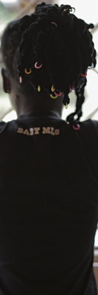 Ung kvinna står med ryggen vänd mot kameran och tittar ut genom ett fönster