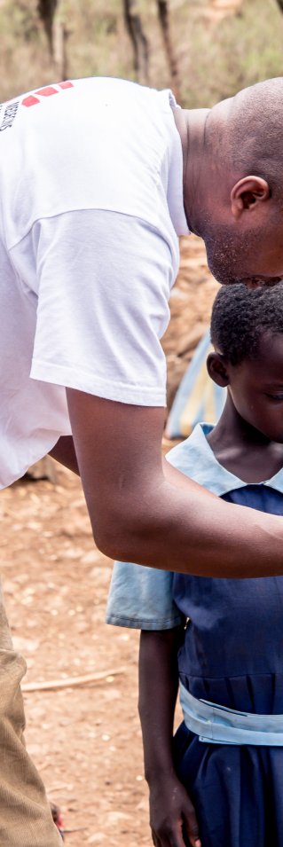 En man i Läkare Utan Gränser t-shirt under en flickas arm som har blivit ormbiten.