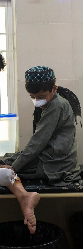 En pojkes sår på benet rengörs av en läkare. Pojken har även bandage på näsan.