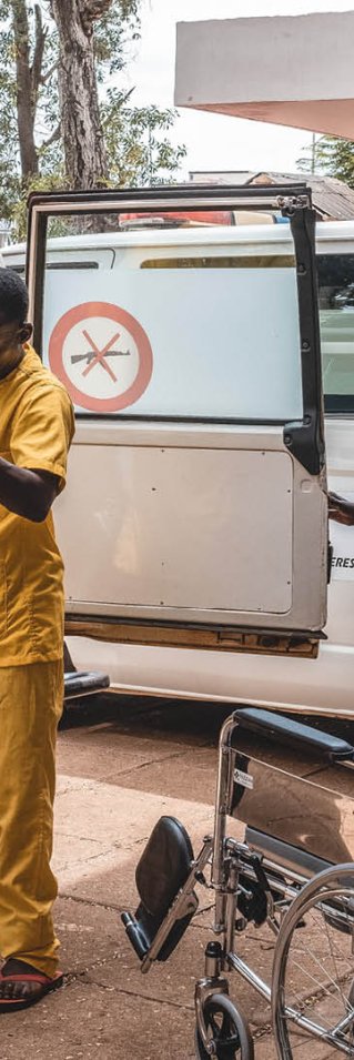 En gravid kvinna hjälps ut från en ambulans utav en person i sjukhuskläder.