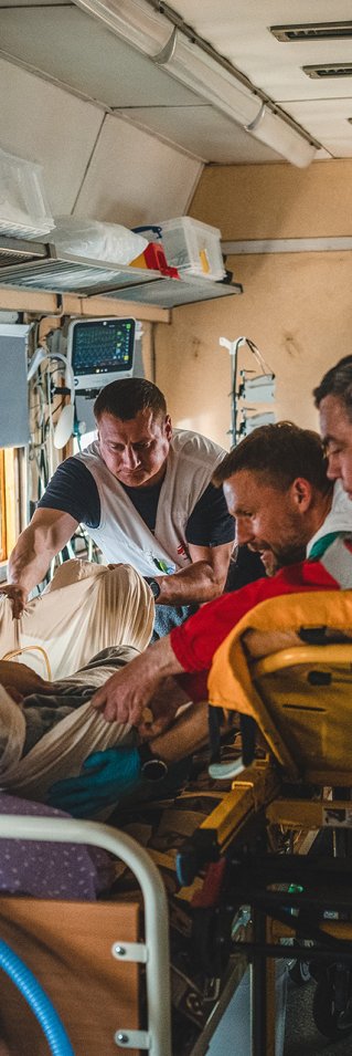 I en tågvagn flyttar Läkare Utan Gränsers personal en patient från en bår till en säng.