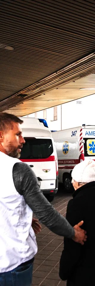 En man i Läkare Utan Gränser väst leder två kvinnor mot ett tåg