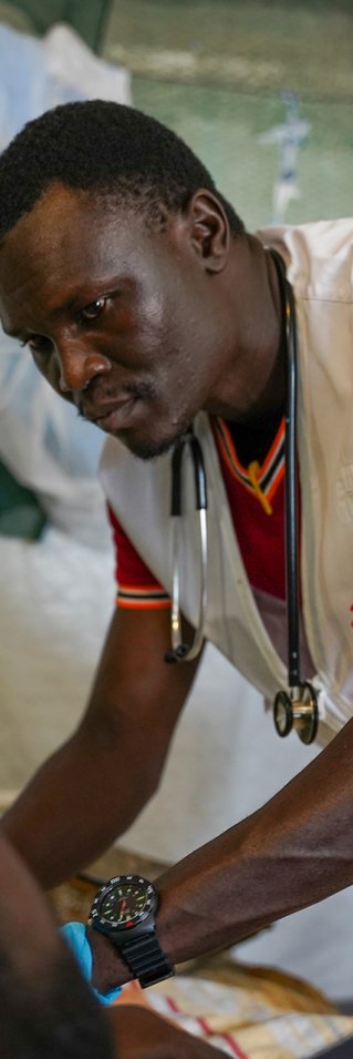 En man står lutad över en patient. 