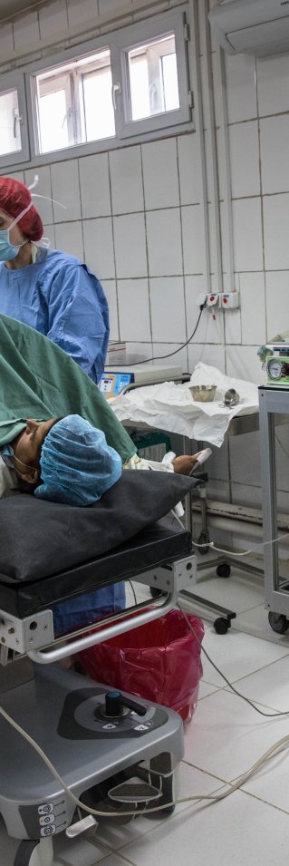 En kvinna ligger på en säng med läkare runt omkring henne