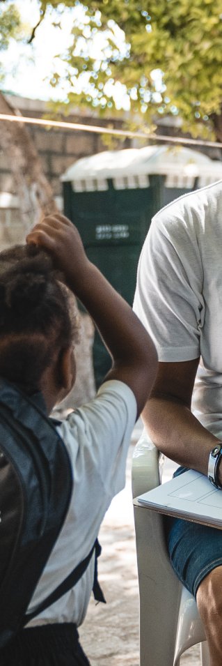 En kvinna i Läkare Utan Gränser T-shirt sitter på en stol framför ett barn.