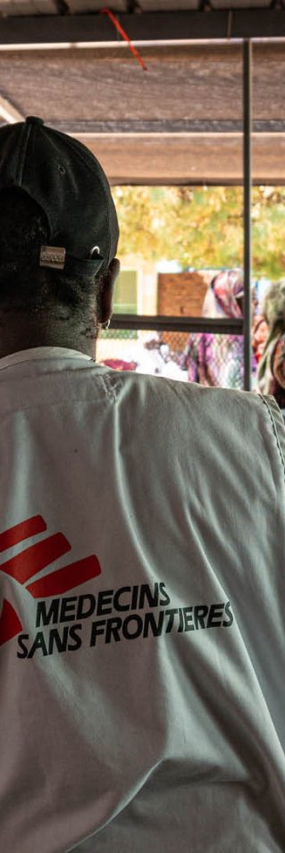 Man med Läkare Utan Gränser väst visar en blankett för en kvinna till vänster om honom