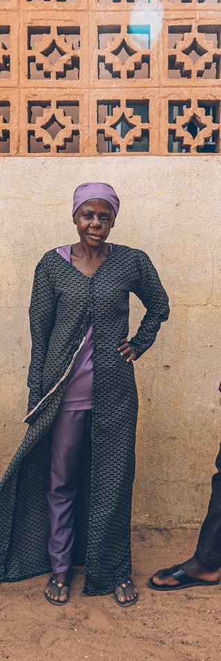 Två män och en kvinna som överlevt noma står med ryggen mot en vägg.