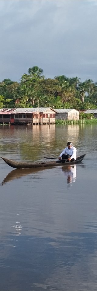 En flod med några enkla träbyggnader i bakgrunden.