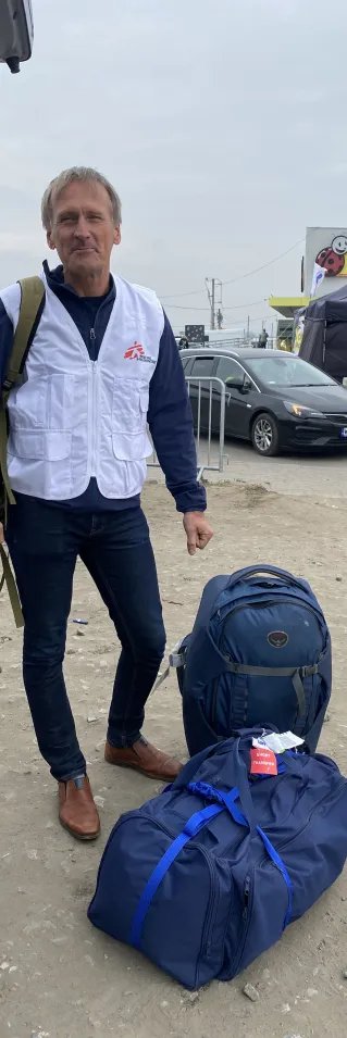 En man med Läakre Utan Gränser väst står bredvid två fullpackade väskor.