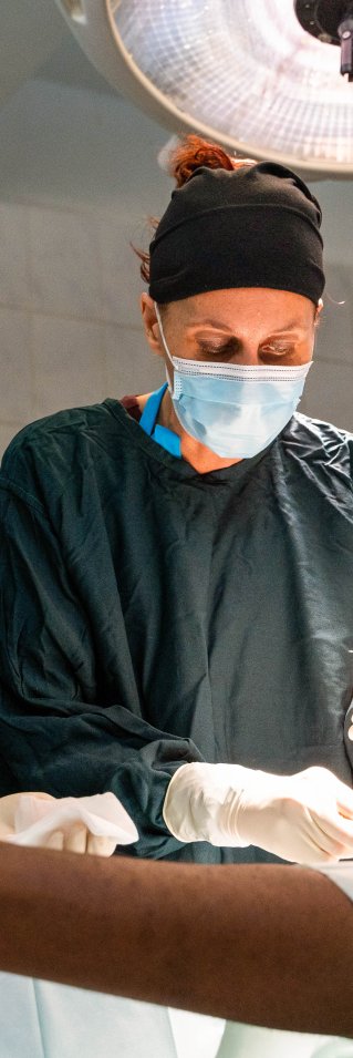 Två personer utför en operation på ett ben som syns i bild. 