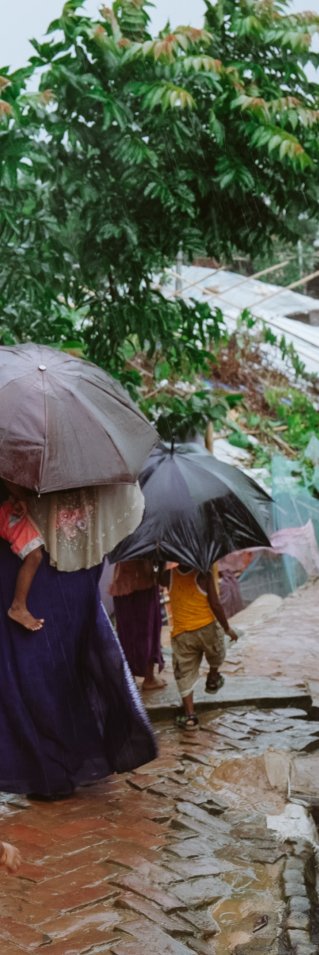 En familj går längs en gata, på båda sidor syns skjul bygda av bambu och plastskivor.