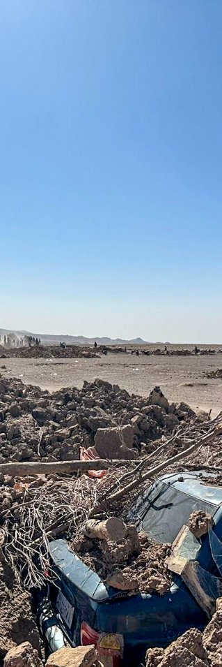 fullständigt raserade hus och en bil täckt av tegelstenar 