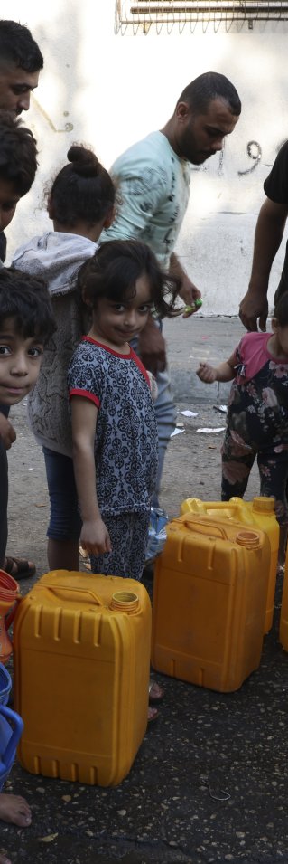 barn och vuxna köar för att hämta vatten vid en vattentank på en lastbil