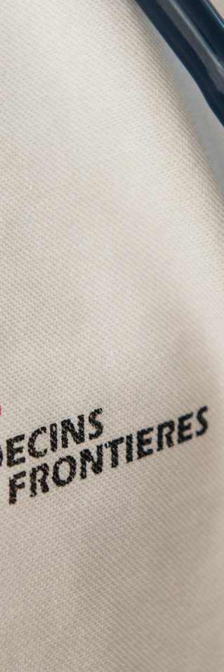 Närbild på Läkare Utan Gränsers logotyp tryckt på vitt tyg, till höger hänger ett stetoskop.