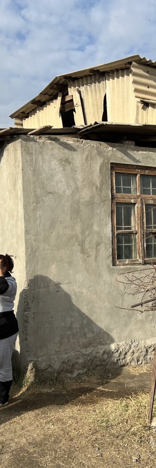En kvinna med Läkare Utan Gränser-väst pratar med en grupp kvinnor utanför ett grått stenhus.