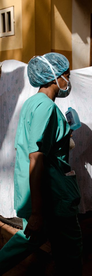 Kvinna iklädd sjukvårdskläder går framför lakan som hänger på tvättlina.
