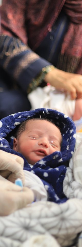 Ett nyfött barn i en filt får vård av en sjuksköterska.