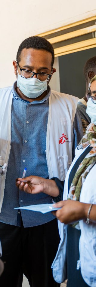 Två kvinnor och en man iklädda Läkare Utan Gränser västar står och pratar med varandra.