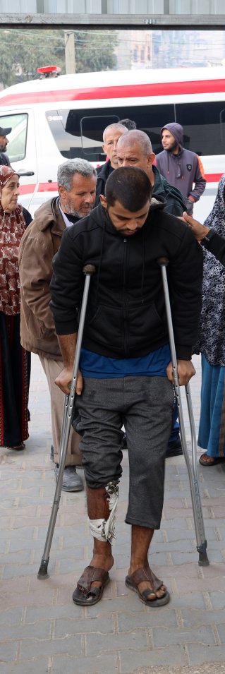 En man på kryckor leds in genom en dörr av en man med Läkare Utan Gränser väst.