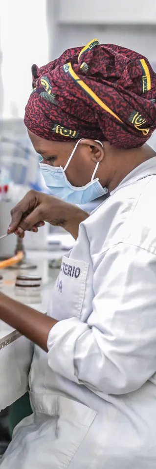 En kvinna i labbkläder och munskydd analyserar bakterieprov i ett laboratorium