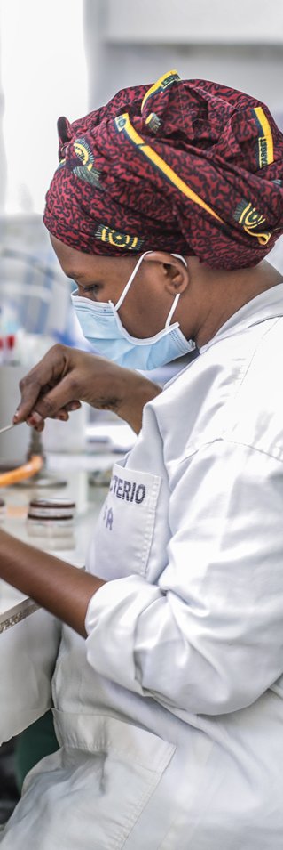 En kvinna i labbkläder och munskydd analyserar bakterieprov i ett laboratorium