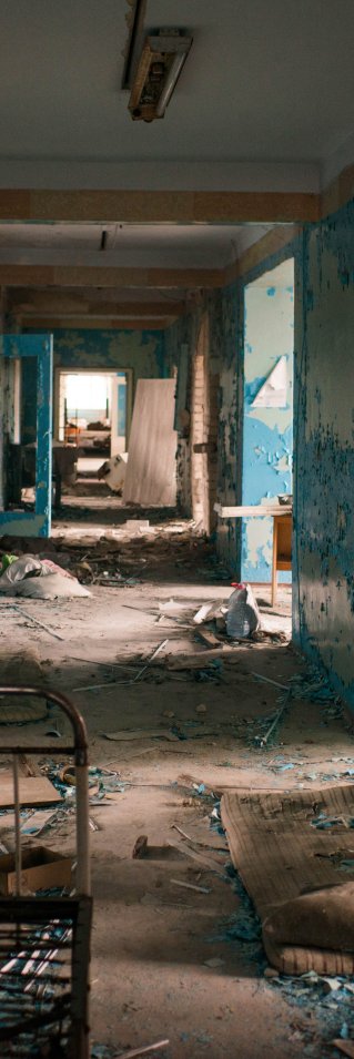 En sjukhuskorridor med blå väggar fylld av söndriga saker.