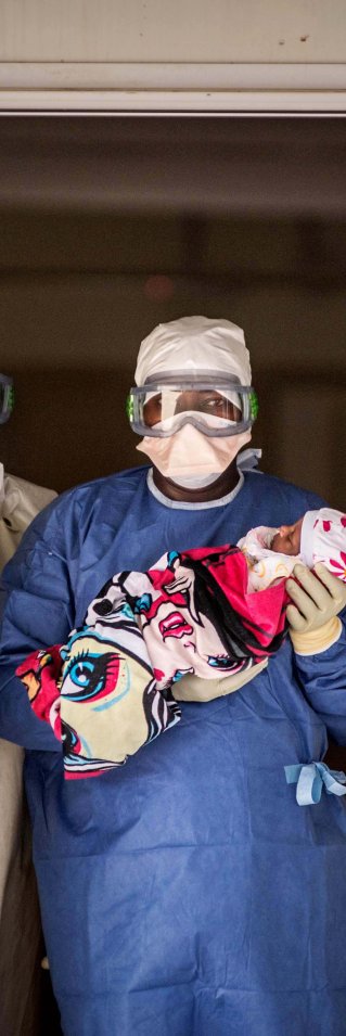 Utrustade läkare kollar in i kameran där en av tre har ett barn i famnen.