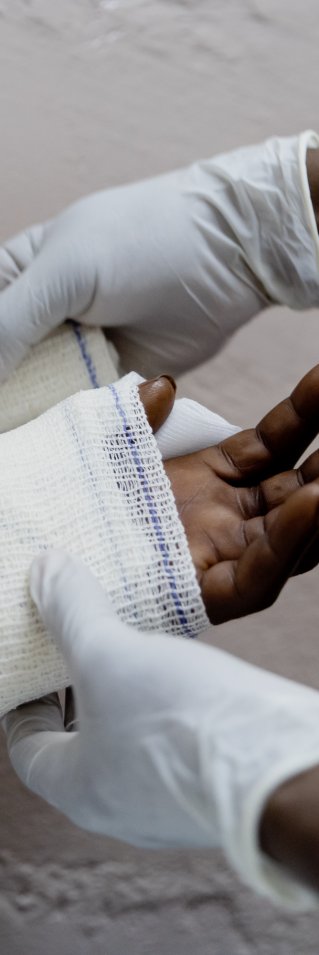 Två händer syns, en hand får bandage.