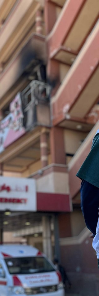 Man i Läkare Utan Gränser-väst utanför en byggnad med spår av angrepp