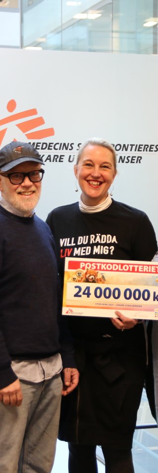 En grupp glada personer håller i en check där det står 24 miljoner