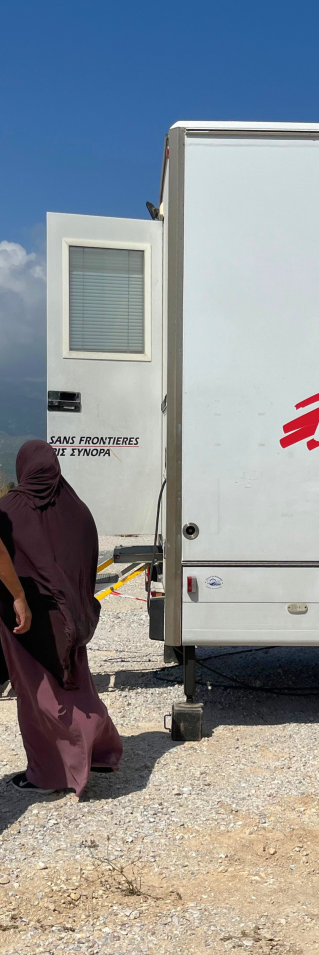 En anställd på Läkare Utan Gränser och en patient går mot mobil klinik