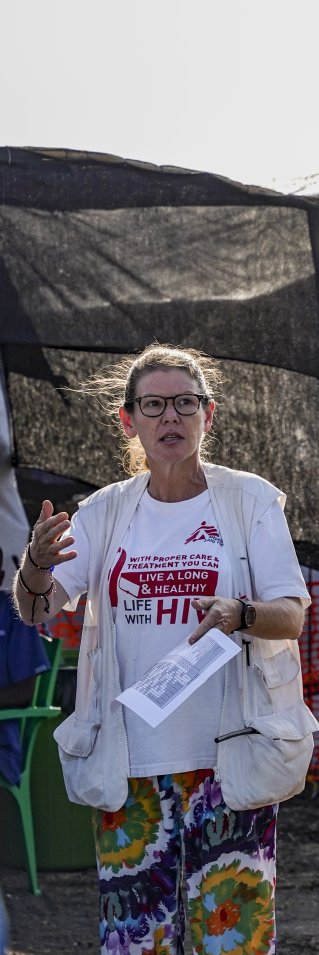 En kvinna i Läkare Utan Gränser-väst står utomhus med vårdklädda personer i en cirkel runt henne.