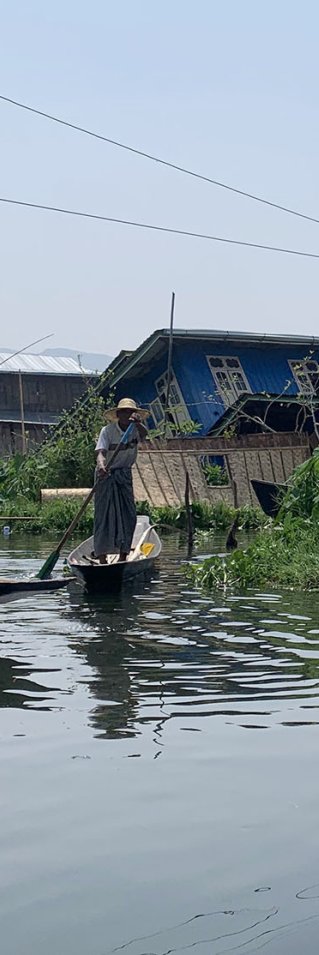 Två män i varsin båt tar sig mellan raserade hus