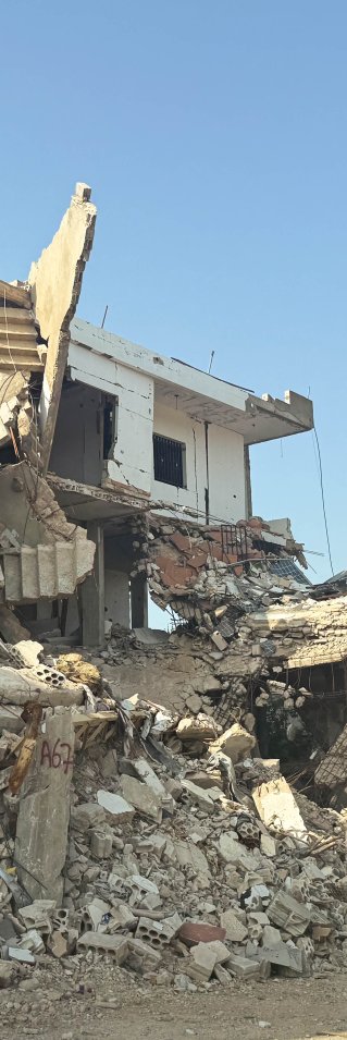 Ett förstört hus med högar av bråte framför.