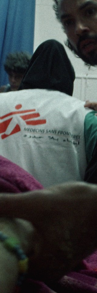 Sjukvårdspersonal, varav flera bär västar med Läkare Utan Gränsers logotyp, tar hand om en patient i ett akutrum