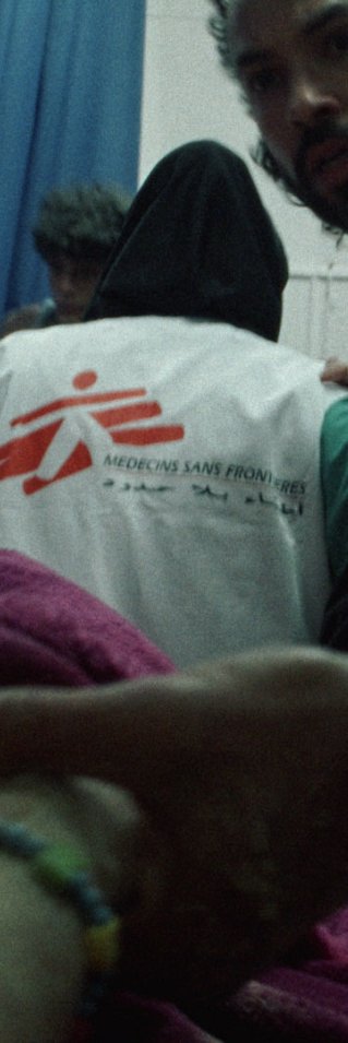 Sjukvårdspersonal, varav flera bär västar med Läkare Utan Gränsers logotyp, tar hand om en patient i ett akutrum