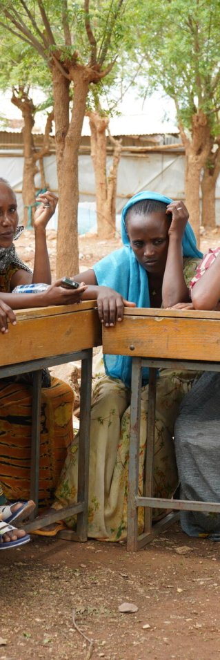 En grupp kvinnor sitter vid ett avlångt bord utomhus.