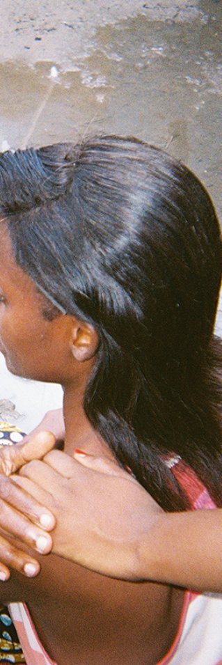 en ung kvinna sitter med ryggen mot kameran och någon lägger sin hand på hennes axel