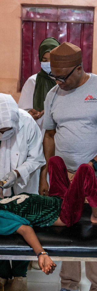 En kvinna och två män hjälper ett barn på en brits på en klinik