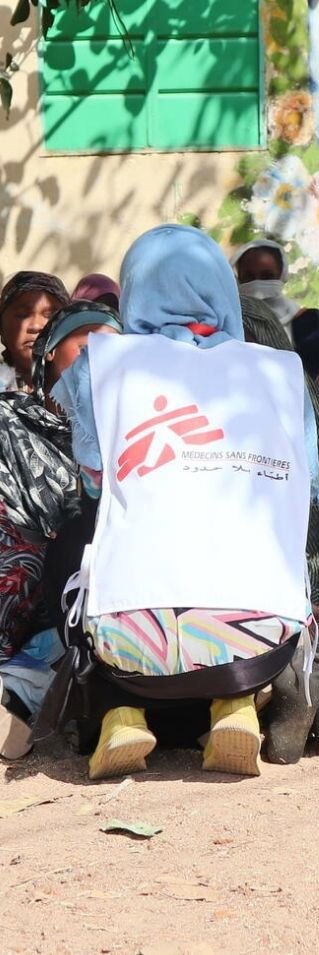 Kvinnor sitter i skuggan av ett träd