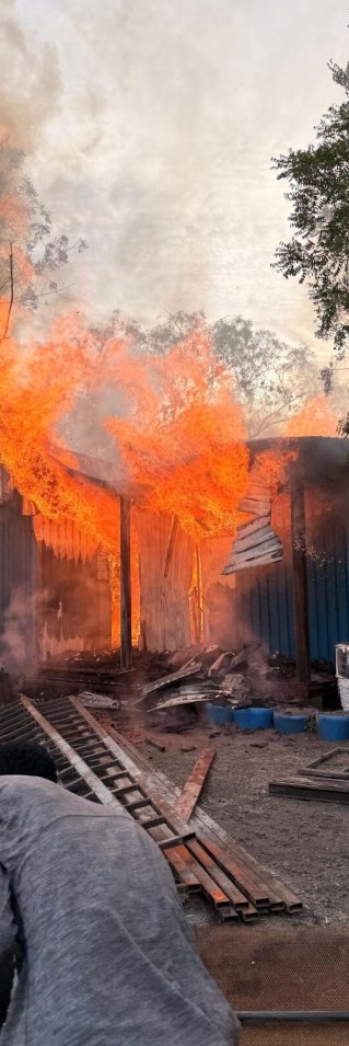 En brinnande byggnad med två människor i förgrunden.