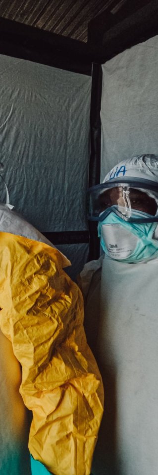 Tre personer i heltäckande eboladräkter står uppradade.
