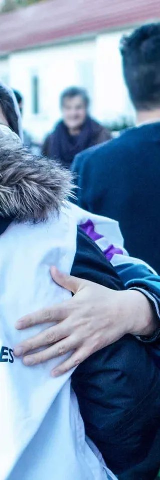 Kvinna i Läkare utan Gränser-väst vänd från kameran kramandes en annan person