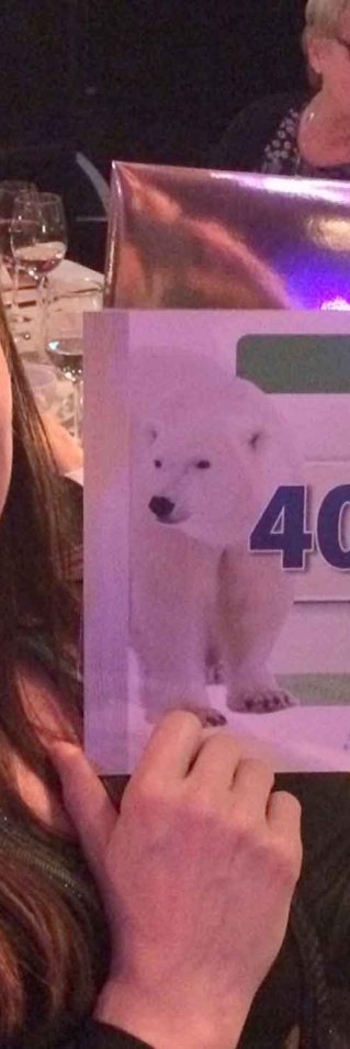 En kvinna håller upp en jättestor check från Postkodlotteriet